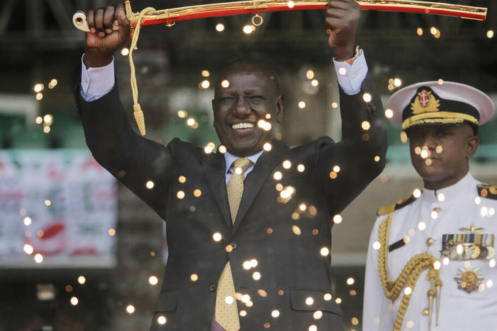 Kenya's new president William Ruto, seen Tuesday behind fountain fireworks, holds up a ceremonial sword as he is sworn in to office at a ceremony held at Kasarani stadium in Nairobi.
