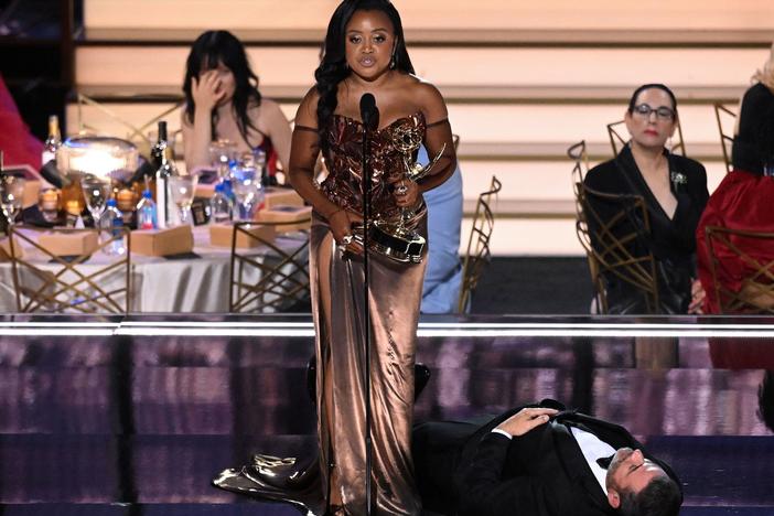 Quinta Brunson accepts the Emmy award for Outstanding Writing For A Comedy Series for "Abbott Elementary" while standing over Jimmy Kimmel.