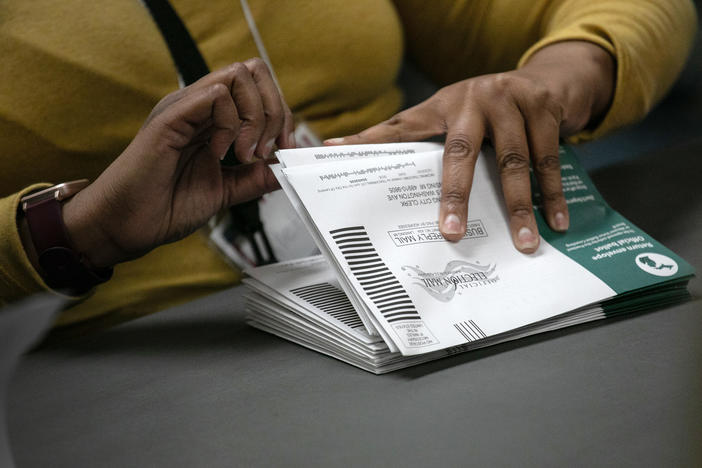 Election workers sort absentee ballots at the Lansing city clerk's office on Nov. 3, 2020, in Lansing, Mich. This fall, Michigan voters will weigh in on an expansive ballot question that would change the voting process.