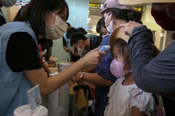 Travel rules and regulations — and national lockdowns — have varied wildly, which gave SARS-CoV-2 lots of opportunities to spread. Above: A young traveler's temperature is checked at Taipei Songshan Airport in July 2020.