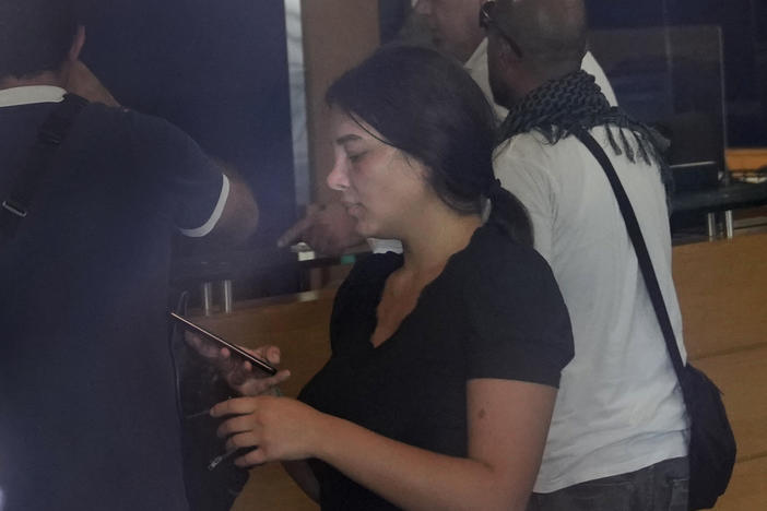 Sali Hafez (center), accompanied by activists, looks at her phone on Wednesday after breaking into a BLOM Bank branch in Beirut, Lebanon, brandishing what she later said was a toy pistol and taking $13,000 from her trapped savings account.