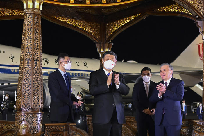 In this photo released by Xinhua News Agency, Chinese President Xi Jinping, center, is welcomed by Uzbekistan President Shavkat Mirziyoyev, right, as he arrives in Samarkand, Uzbekistan.