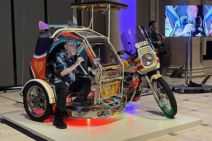 A participant sings karaoke inside "TNT Traysikel," a mobile artwork by Paolo Asuncion and Michael Arcega, two students of Carlos Villa. The piece is part of the Villa retrospective at the Asian Art Museum in San Francisco.