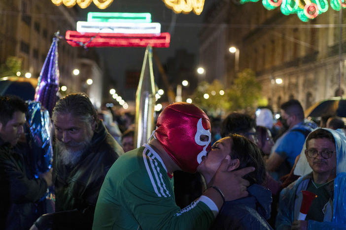 A man wearing a Lucha Libre wrestler's mask kisses a woman during the Independence Day celebrations at Mexico City's main square, the Zócalo.