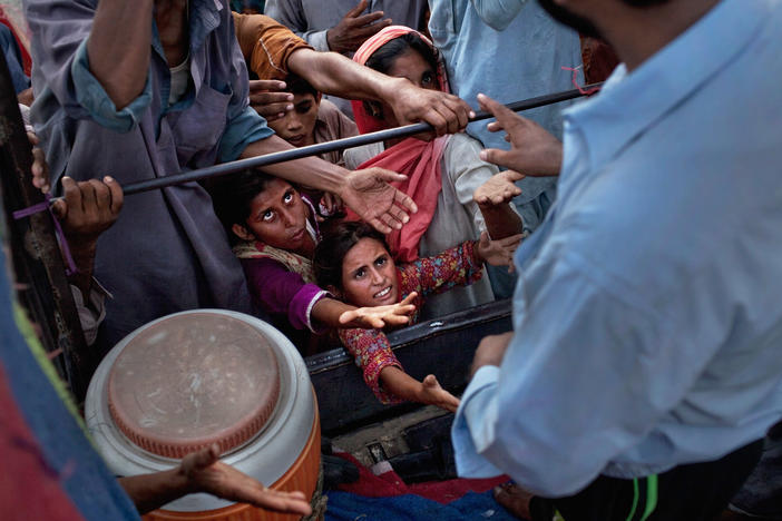 Children reach for food handouts in the aftermath of the catastrophic flooding in Pakistan, which has destroyed rice, corn and wheat crops and left over a third of the country under water.