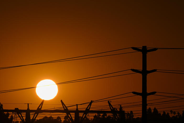 A spike in natural gas prices amid a hot summer is contributing to high electricity bills across the United States. Here, the sun sets behind electric power lines in Redondo Beach, Calif., on Aug. 31.