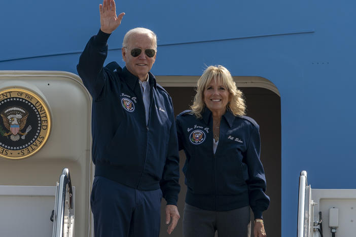 President Biden waves as first lady Jill Biden watches standing at the top of the steps of Air Force One before boarding at Andrews Air Force Base, Md., on Saturday.
