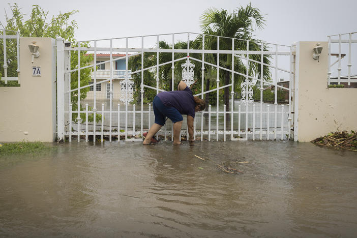 A woman clears debris on her property flooded by Hurricane Fiona in Salinas, Puerto Rico, Monday, Sept. 19, 2022.