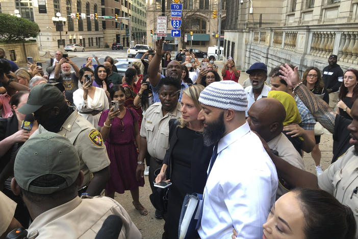 Adnan Syed, center, leaves the Cummings Courthouse in Baltimore on Monday. A judge has ordered the release of Syed after overturning his conviction for a 1999 murder that was chronicled in the hit podcast <em>Serial</em>.