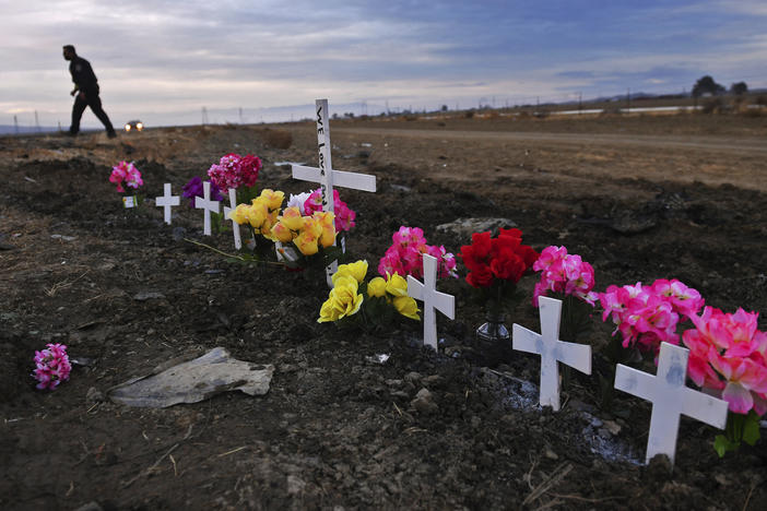 A row of crosses form a memorial along Highway 33 as police officers survey the scene a day after a crash killed nine people south of Coalinga, Calif., on Jan. 2, 2021.