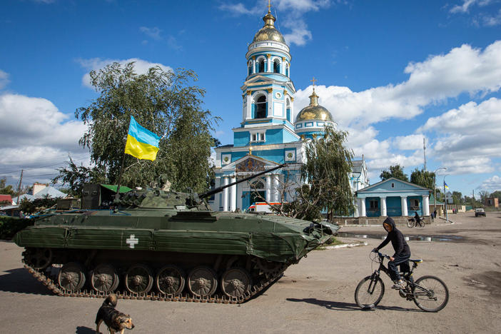 A boy rides a bicycle near an armored tank with a Ukrainian flag in the town of Izium, recently liberated by Ukrainian armed forces, in the Kharkiv region on Monday. Russian troops occupied Izium on April 1.