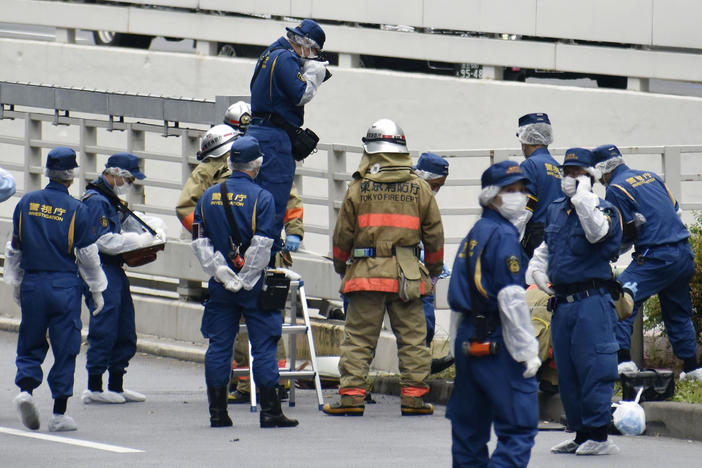 Police and firefighters inspect the scene where a man is reported to set himself on fire, near the Prime Minister's Office in Tokyo on Wednesday.
