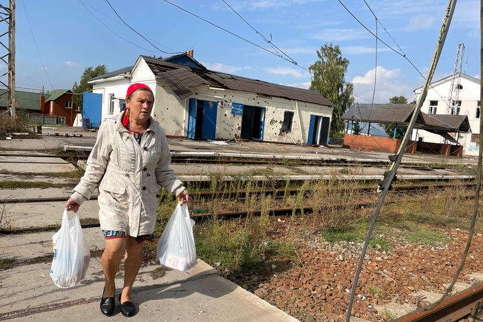 Luda Toryanyk, 58, walks across the railroad tracks in Kozacha Lopan, Ukraine, on Sunday. The village was retaken by Ukrainian troops on Sept. 11 after being occupied by Russian forces for more than six months. Toryanyk carries home bags of food that Ukrainian volunteers were distributing in the center of the village.