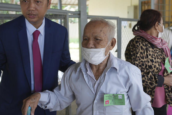 Bou Meng, second from left, former prison survivor, is helped into the courtroom before the hearings against Khieu Samphan, former Khmer Rouge head of state, in Phnom Penh, Cambodia, Thursday, Sept. 22, 2022.