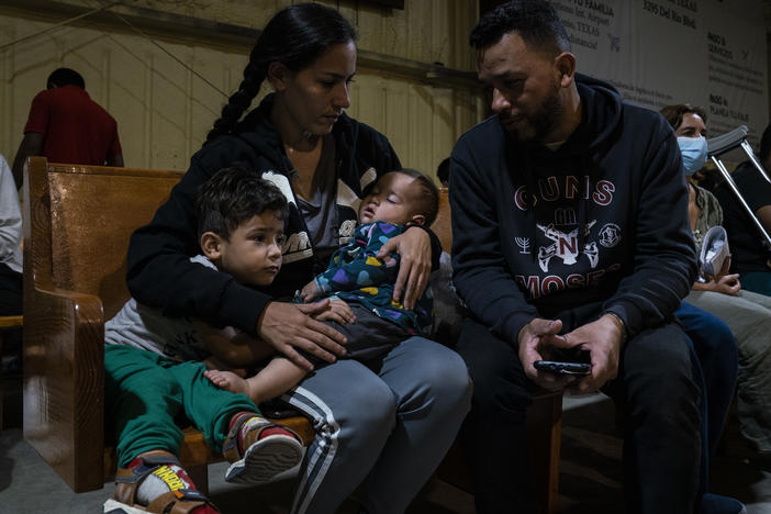 Venezuelan migrants Kimberly González and Denny Velasco and their children wait for a bus at Mission: Border Hope in Eagle Pass, Texas.