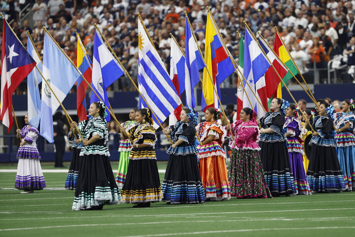 Women hold flags during the national anthem in honor of Hispanic Heritage Month before an NFL game on Sept. 18. The NFL has launched its Por La Cultura campaign.