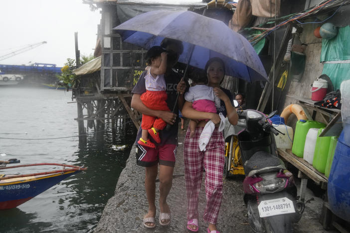 Residents of the Tondo district in Manila carry their children as they evacuate to safer grounds on Sunday before Typhoon Noru arrives in the Philippines.