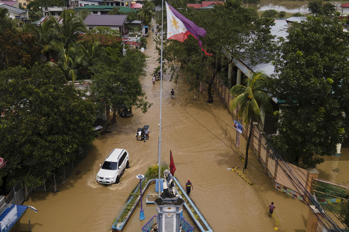 Residents pass by a flooded road from Typhoon Noru in San Miguel town, Bulacan province, Philippines. Typhoon Noru blew out of the northern Philippines on Monday, leaving some people dead, causing floods and power outages and forcing officials to suspend classes and government work in the capital and outlying provinces.