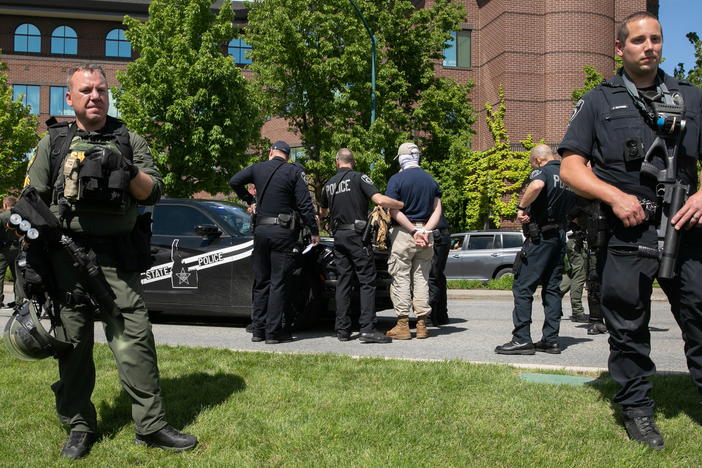 A police officer holds one of a group of men, among 31 arrested for conspiracy to riot and affiliated with the white nationalist group Patriot Front, after they were found in the rear of a U-Haul van in the vicinity of a North Idaho Pride Alliance LGBTQ+ event in Coeur d'Alene, Idaho, on June 11, 2022.