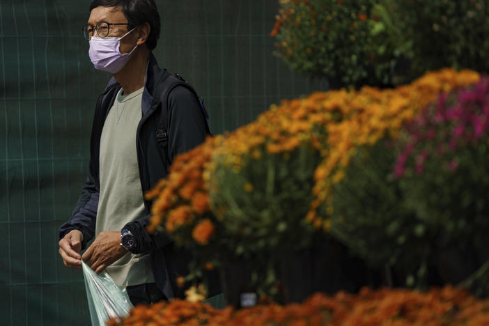 A person wearing a mask walks past a flower display in front of a supermarket on Front Street East in Toronto on Sept. 16.