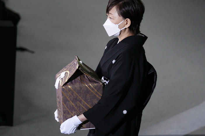 Akie Abe, wife of former Prime Minister Shinzo Abe, carries a cinerary urn containing his ashes at his state funeral, Tuesday, Sept. 27, 2022, in Tokyo.