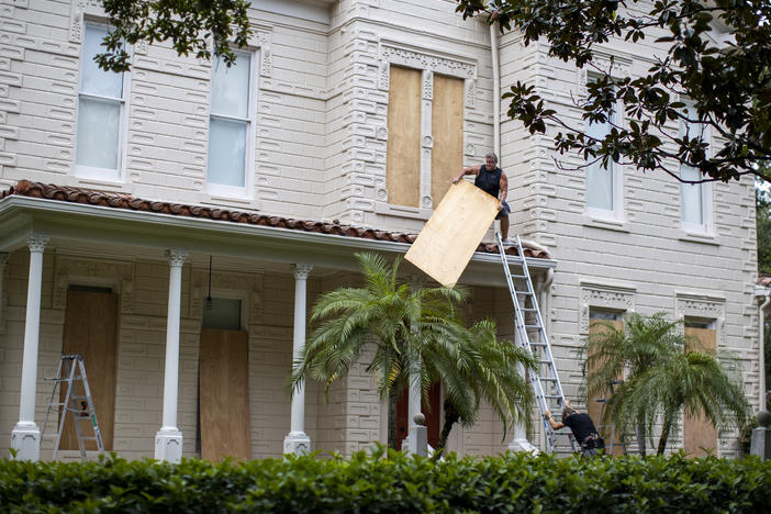 Two people work on boarding up a house in South Tampa Bay, Florida, on Tuesday, before Hurricane Ian hits the area.