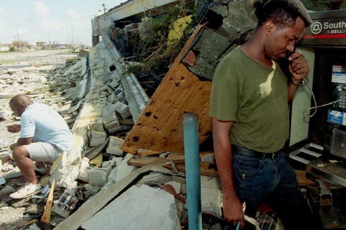 A South Miami, Fla., resident makes a phone call from one of the few working phones in the area as another man waits for his turn amid the rubble of a destroyed business on Aug. 25, 1992, after Hurricane Andrew made landfall.