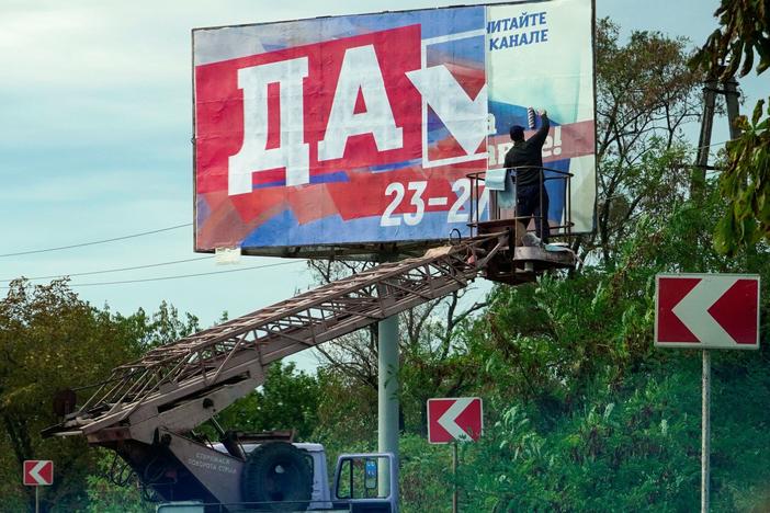 A man glues a referendum poster reading "Yes" in Berdyansk, Ukraine, on Monday.