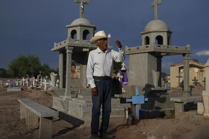Guillermo Rojo, the father of slain water-defense leader Tomás, prays next to his tomb, decorated with a blue cross, at the cemetery in Potam, Mexico, Tuesday, Sept. 27, 2022.