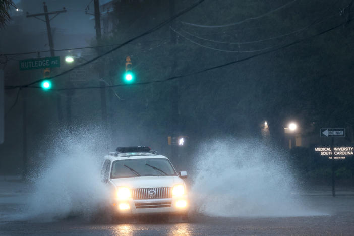 A vehicle is driven down a flooded street in Charleston, S.C., as rain from Hurricane Ian drenches the city on Friday.