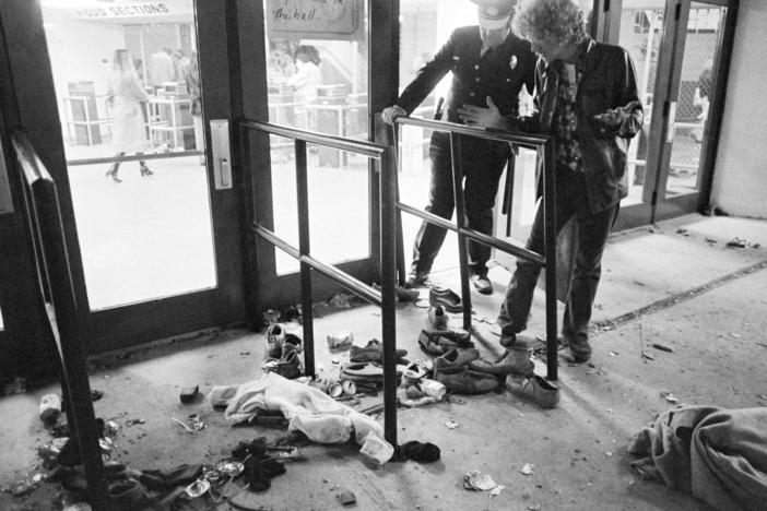 A security guard and an unidentified man look at an area where several people were killed as they were caught in a surging crowd entering Cincinnati's Riverfront Coliseum for a concert by The Who on Dec. 3, 1979.