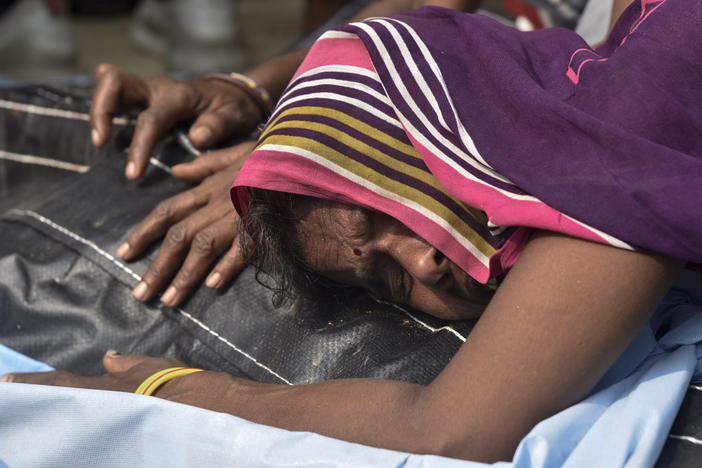 A relative mourns near the body of one of victims of a road accident in Kanpur, Uttar Pradesh state, India, Sunday, Oct.2, 2022. A farm tractor pulling a wagon loaded with people overturned and fell into a pond in Kanpur city's Ghatampur area Saturday night killing 26 people, most of them women and children.