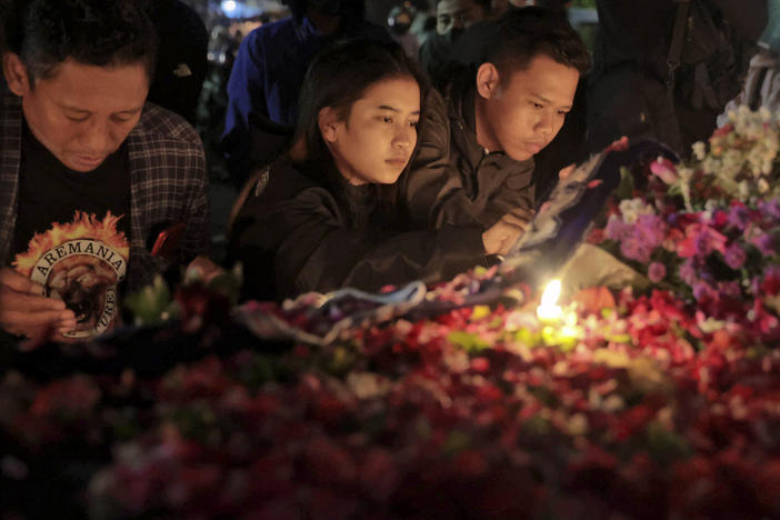 People lay flowers during a candle light vigil for the victims of Saturday's soccer riots outside Kanjuruhan Stadium where it broke out, in Malang, East Java, Indonesia, Sunday, Oct. 2, 2022.