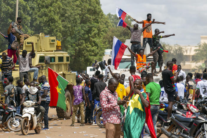 Supporters of Capt. Ibrahim Traore cheer with Russian flags in the streets of Ouagadougou, Burkina Faso, on Sunday. Burkina Faso's new junta leadership is calling for calm after the French Embassy and other buildings were attacked.