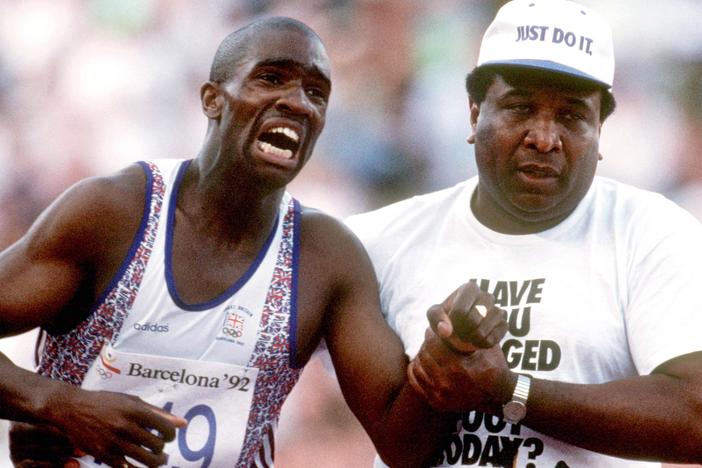 Great Britain's Derek Redmond limps to the finish line after tearing his hamstring at the 1992 Olympic Games, helped by his father Jim.