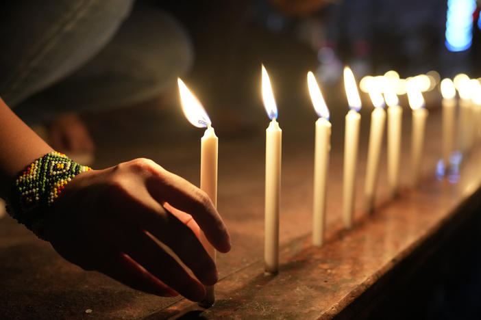 Activists light candles as they condemn the killing of Filipino journalist Percival Mabasa during a rally in Quezon, Philippines, Tuesday Oct. 4, 2022.