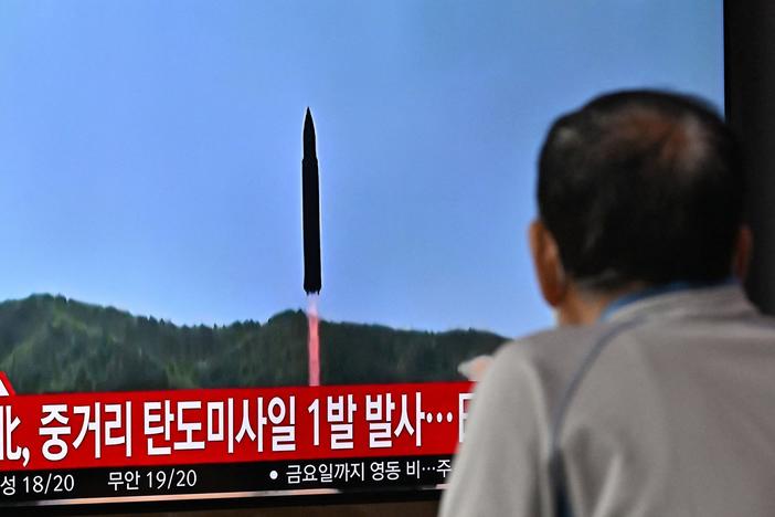 A man watches a television screen showing a news broadcast with file footage of a North Korean missile test, at a railway station in Seoul on October 4, 2022.