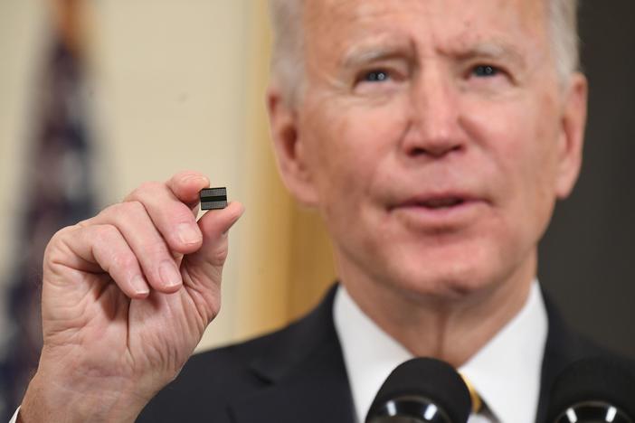 President Biden holds a semiconductor chip in this 2021 file photo. The White House is working out how to spend $52 billion that Congress has provided to spur U.S. chip manufacturing plants.