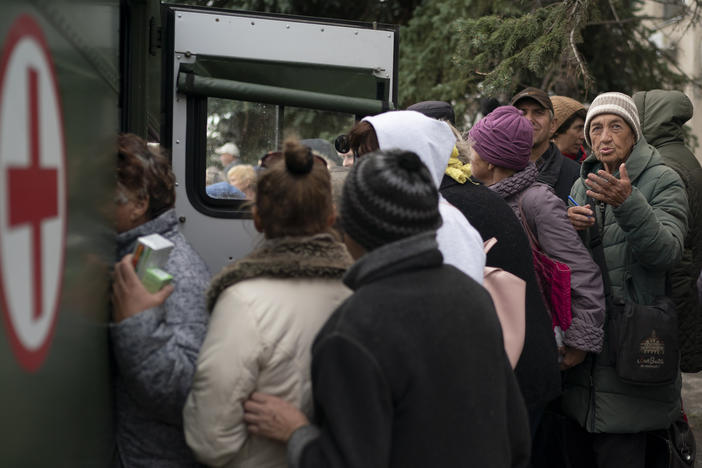 People wait in line as humanitarian aid is distributed at the recaptured town of Lyman, Ukraine, Wednesday, Oct. 5, 2022.