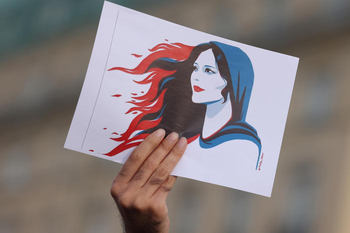 A protester holds a drawing of Mahsa Amini during a demonstration in Berlin, Germany, on Sept. 23. Amini was arrested by Iranian authorities in Tehran on Sept. 13 for not wearing her headscarf properly. She died three days later, apparently due to a severe head injury.