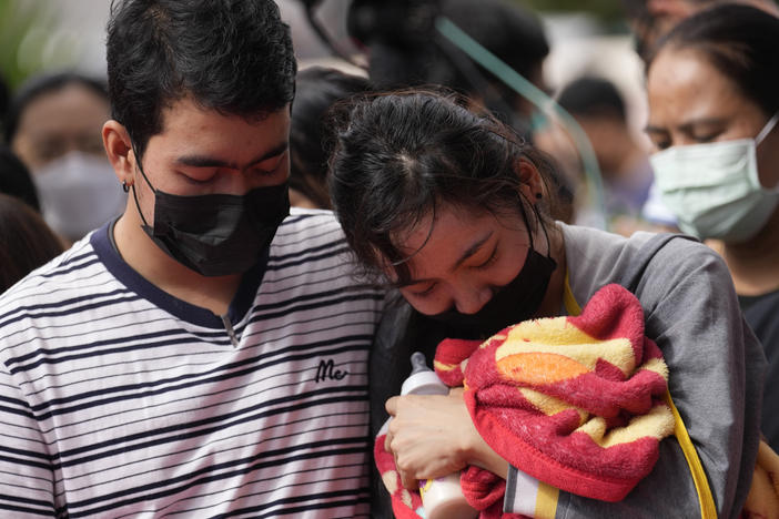 A family of a victim mourns as they bring a blanket and a milk bottle during a ceremony for those killed in the attack on the Young Children's Development Center in the rural town of Uthai Sawan, north eastern Thailand, Friday, Oct. 7, 2022.