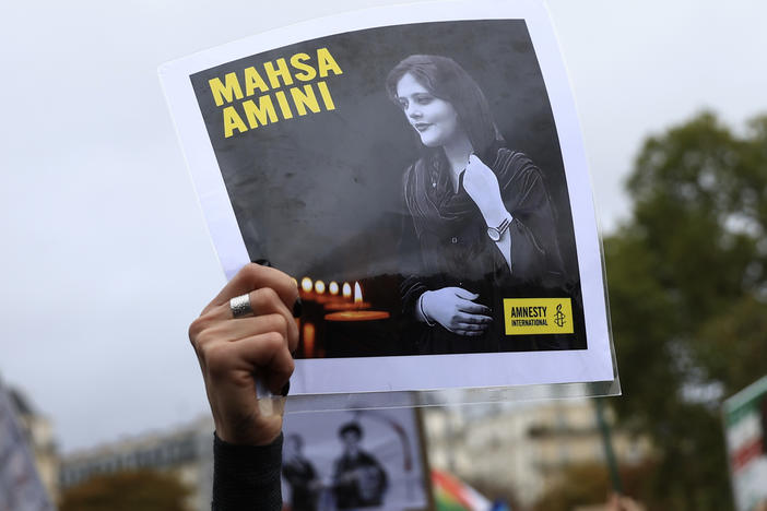 A protester shows a portrait of Mahsa Amini during a demonstration to support Iranian protesters standing up to their leadership over the death of a young woman in police custody, Sunday, Oct. 2, 2022 in Paris.