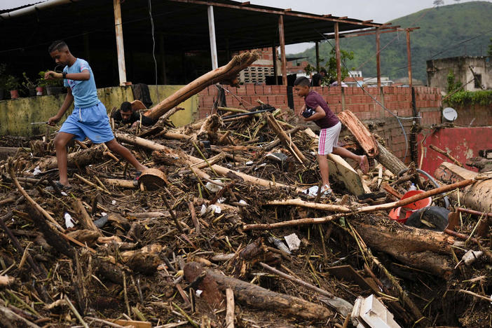 A boy carries sneakers he found amidst the rubble caused by flooding in Las Tejerias, Venezuela, Sunday, Oct. 9, 2022.