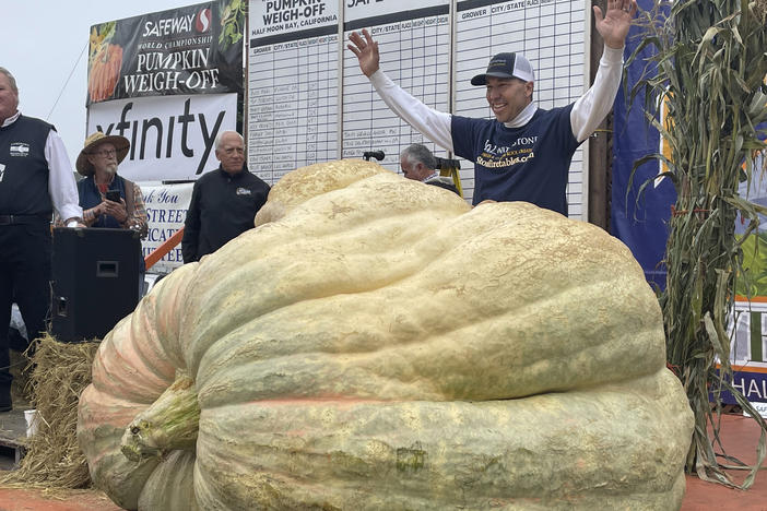 Travis Gienger from Anoka, Minn., stands behind his winning pumpkin at the 49th World Championship Pumpkin Weigh-Off in Half Moon Bay, Calif., on Monday.