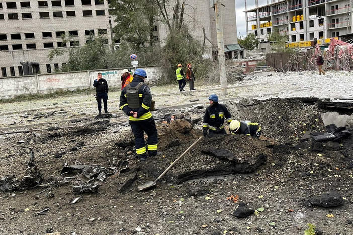 Emergency workers clear debris from the crater of a missile strike at a bus stop in a residential area of Dnipro, Ukraine. Missiles struck multiple cities across the country Monday morning.