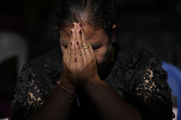 The relative of a victim in a mass killing attack prays for a Buddhist ceremony inside Wat Rat Samakee temple in Uthai Sawan, north eastern Thailand, Tuesday, Oct. 11, 2022.