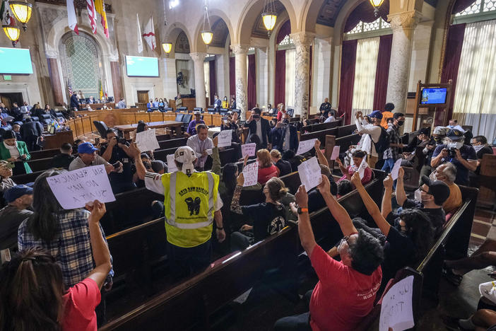 People hold signs and shout slogans as they protest before the cancellation of the Los Angeles City Council meeting Wednesday in Los Angeles.