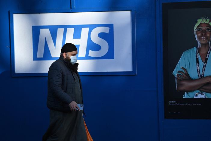 A person walks past images of workers with the United Kingdom's National Health Service posted outside a temporary field hospital in south London on Jan. 5.