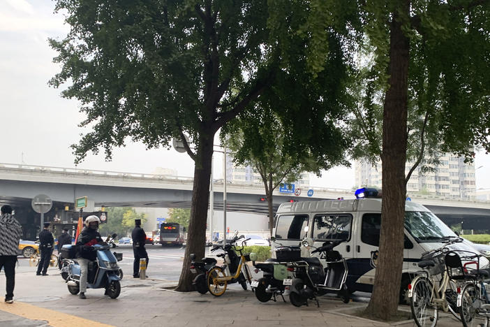 A police vehicle is parked near a bridge where social media videos earlier appeared to show smoke and protest banners in Beijing on Thursday. China's internet censors moved quickly to scrub social media posts after reports of banners criticizing the Communist leadership being hung from a busy intersection in the capital Beijing.