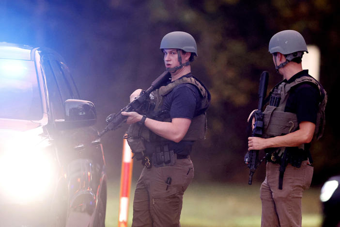 Law enforcement stand at the entrance to Neuse River Greenway Trail parking at Abington Lane following a shooting in Raleigh, N.C., Thursday, Oct. 13, 2022.